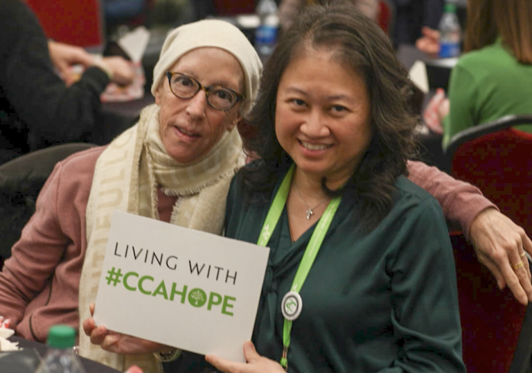 Cholangiocarcinoma community members hold up a sign that says 